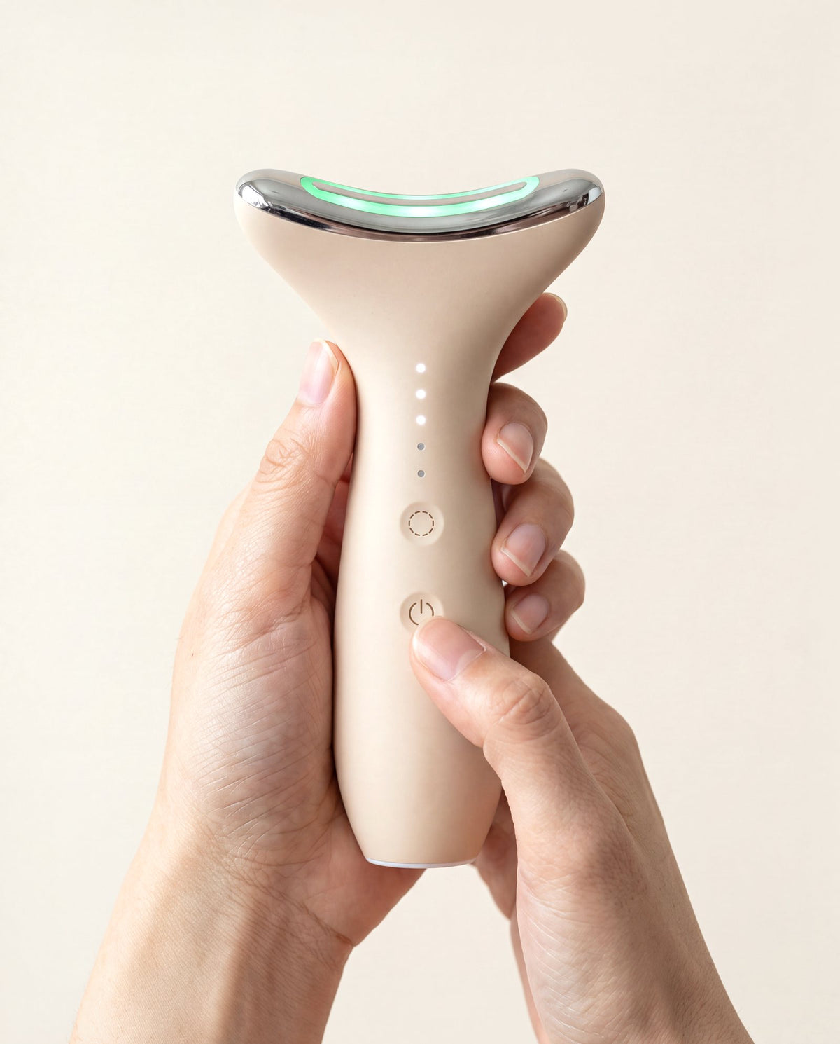 Hands holding Loomi Glide, a thumb on the power button, the head lit green.